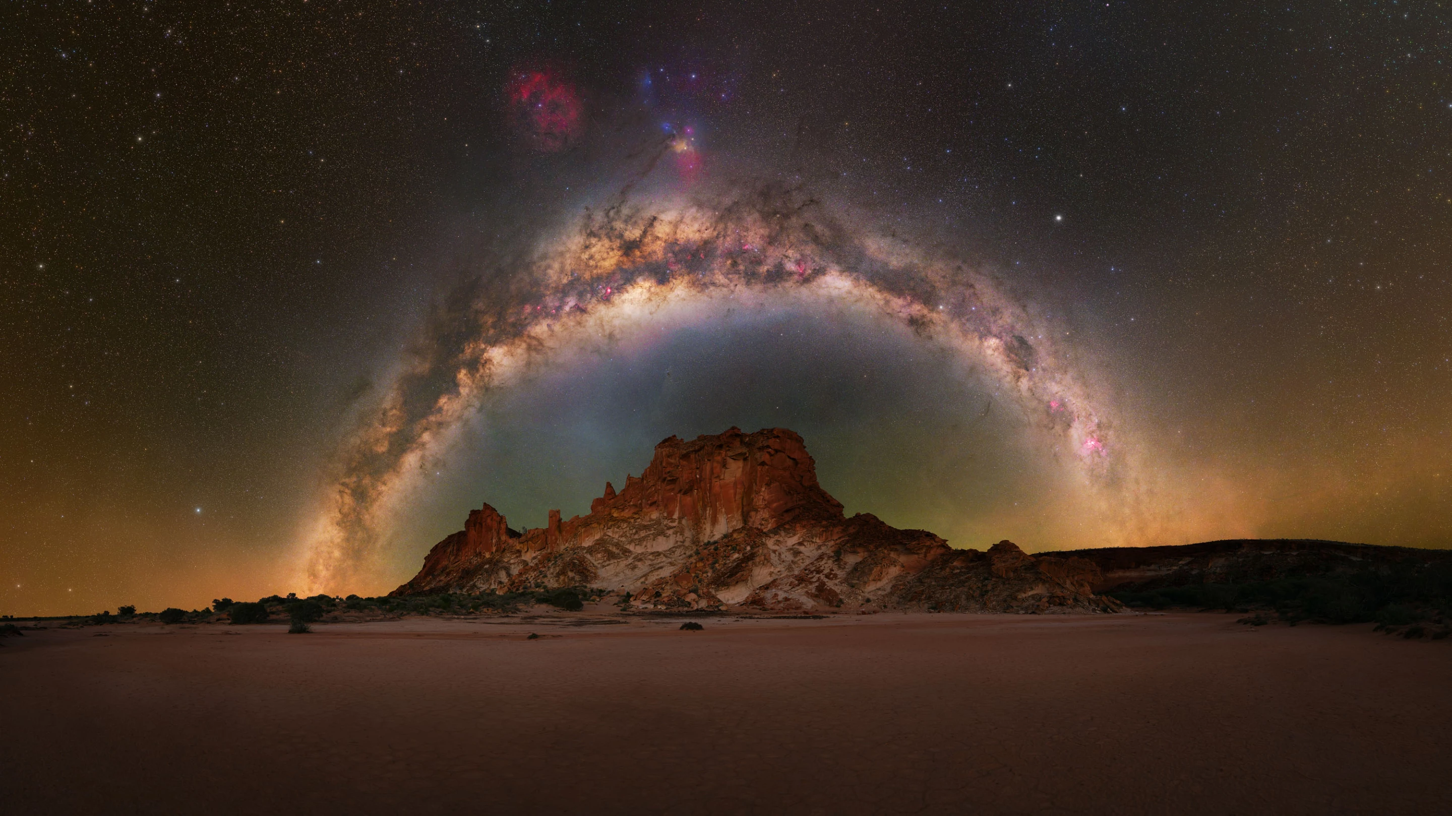 Rainbow Valley, by Baillie Farley, shot in Australia. The Milky Way arches over a sandstone formation in the outback.