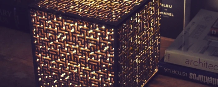 The Golden Cube is a cube-shaped lamp with cardboard cut into intricate maze-like patterns to house the bulb