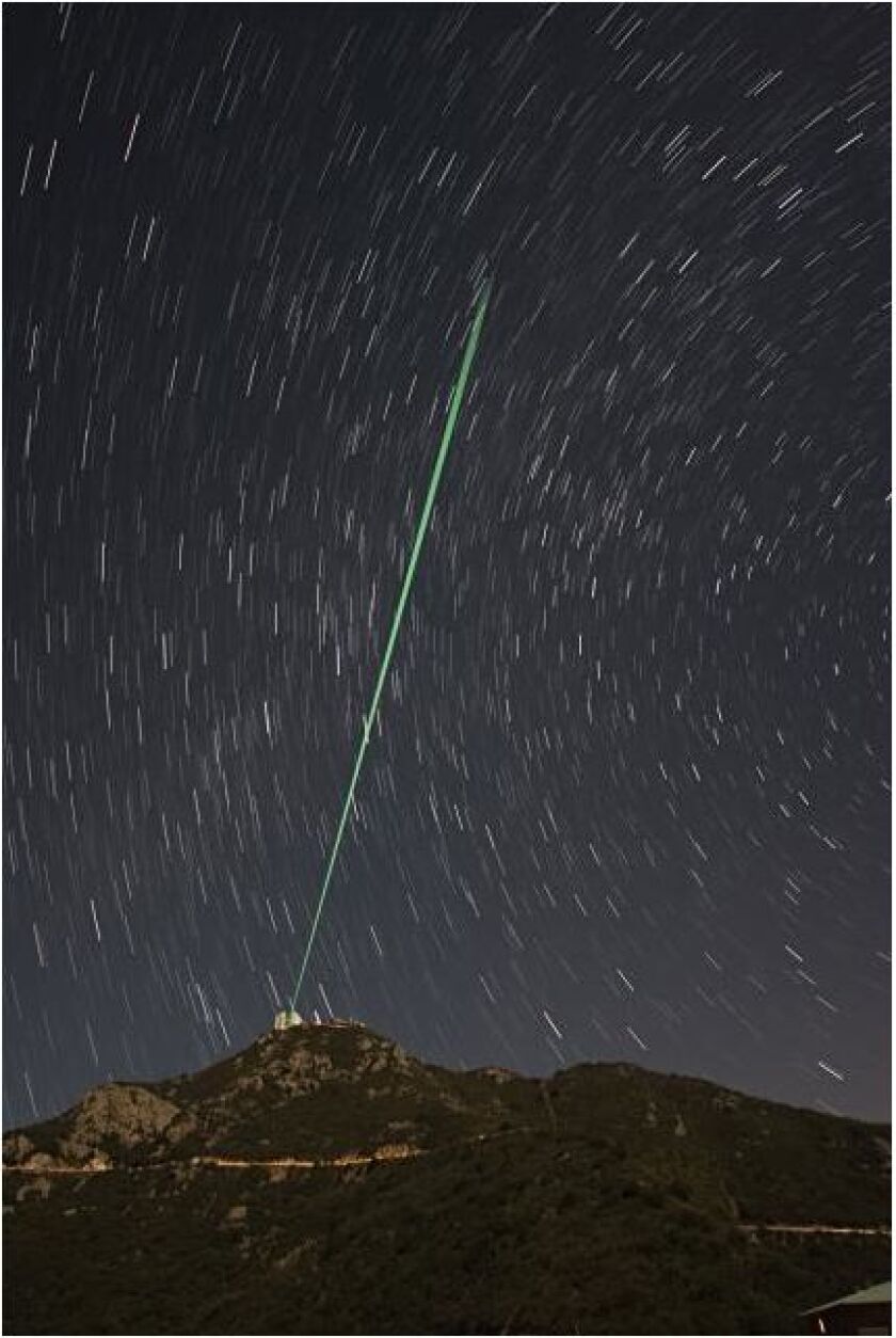 The system's green lasers shooting into the night-time sky over the MMT Observatory