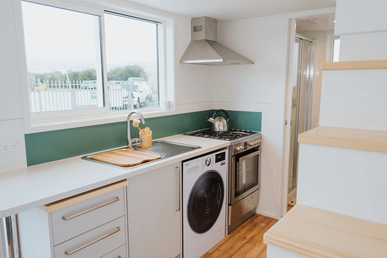 The Dance Tiny House's kitchen includes an oven, washing machine, sink, cabinetry, and fridge/freezer