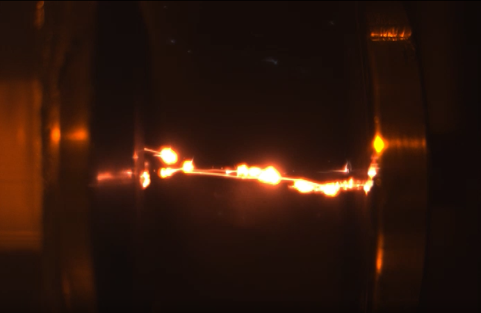 Electrical sparks propagate along a chain of graphene microparticles in a tractor beam. In this test the electrodes are 30 mm apart, three times further apart than other runs