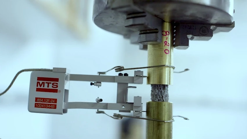 A piece of 3D-printed bone-like material (gray) is subjected to cyclic load testing