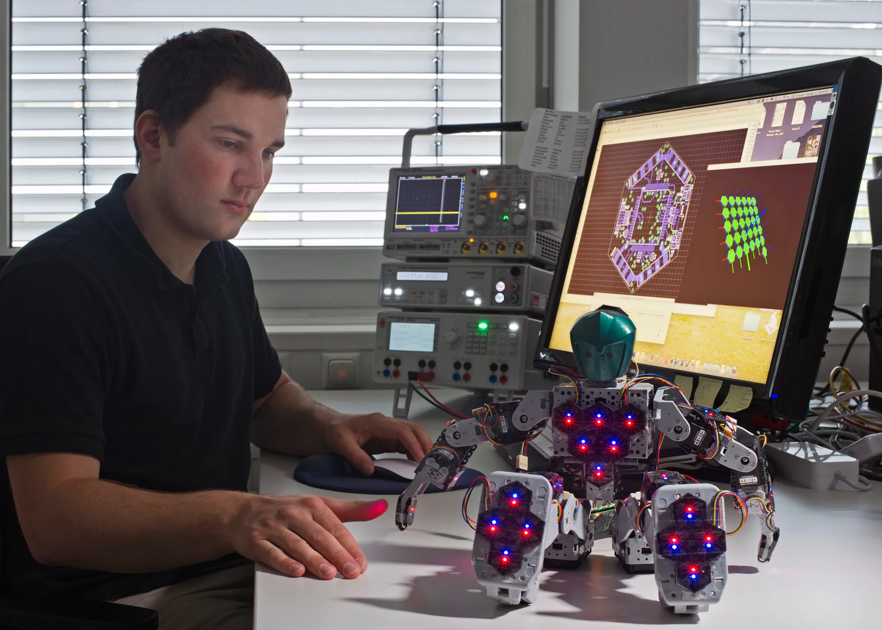 Engineer Philip Mittendorfer with the Bioloid Robot with 31 hexagonal sensor modules distributed throughout its body (Image: Andreas Heddergott / TU Munich)