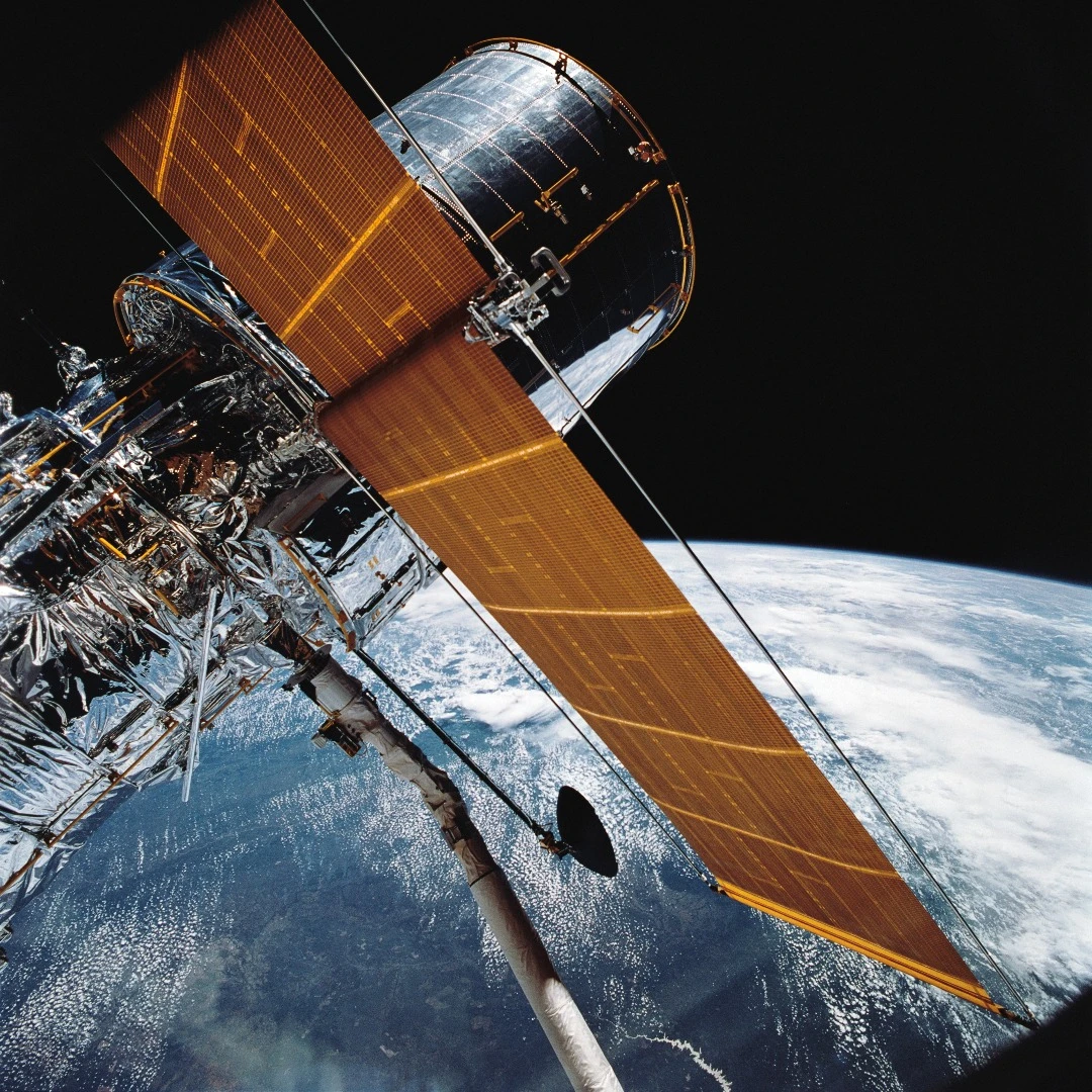 Image of the Hubble Space Telescope in orbit around Earth as seen from the Space Shuttle Discovery during deployment in Apr. 1990