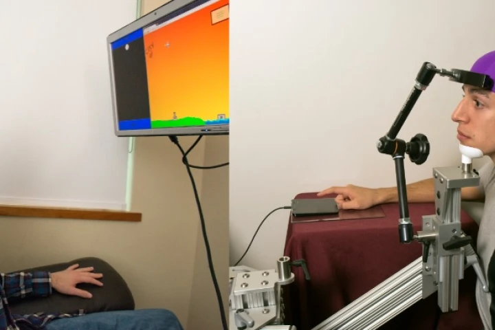 A subject's hand was moved remotely by having one subject thinking about moving their hand to play a video game (Photo: Mary Levin, University of Washington)