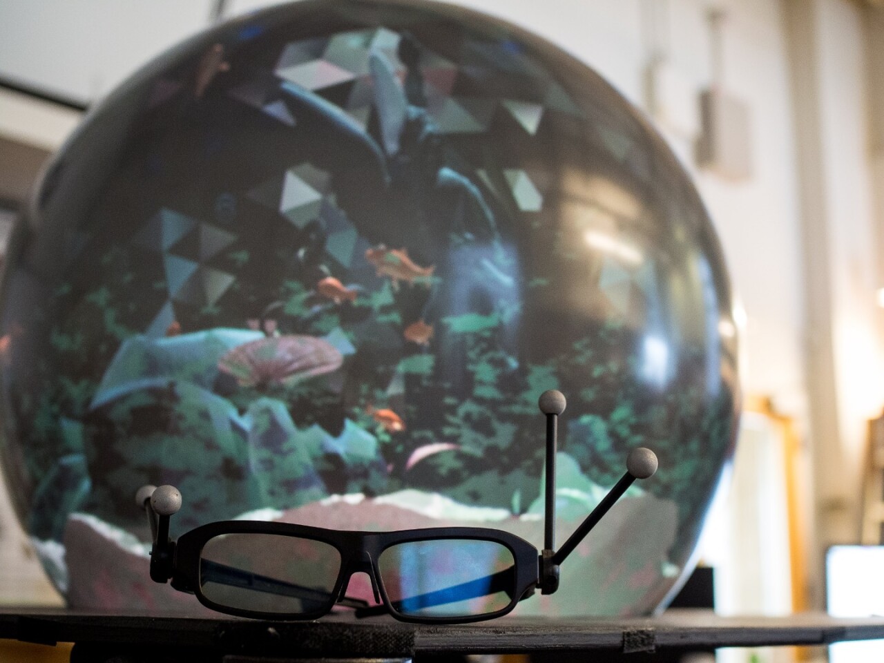 The system appears to use motion-trackable frequency separation glasses, enabling it to create a different image from up to two points of view