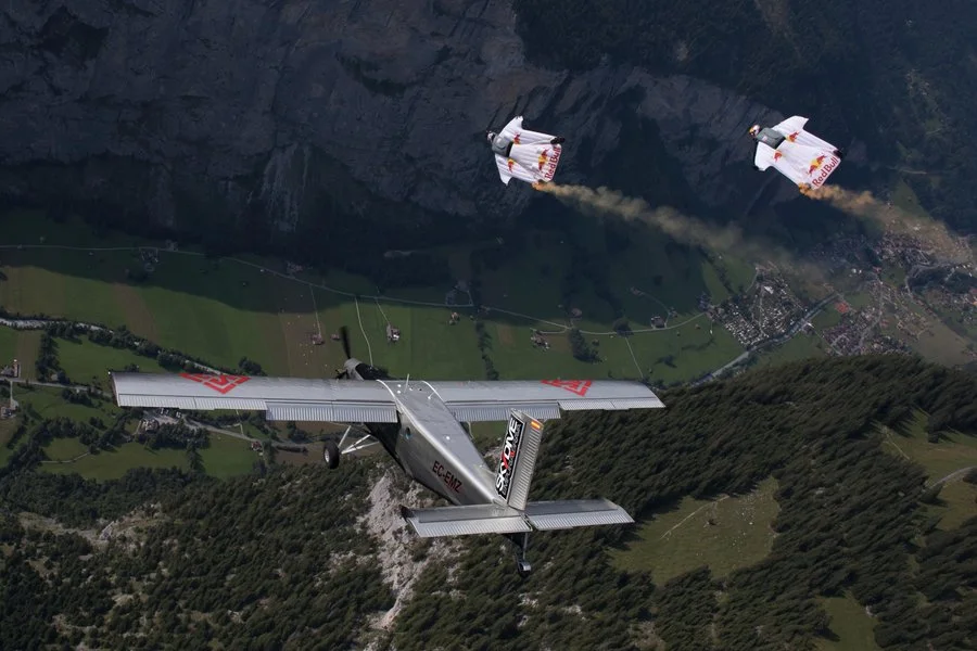 Wingsuit flyers try to catch up with a plane in mid-air