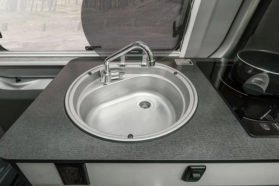 The kitchen sink includes a fold-down faucet and glass cover