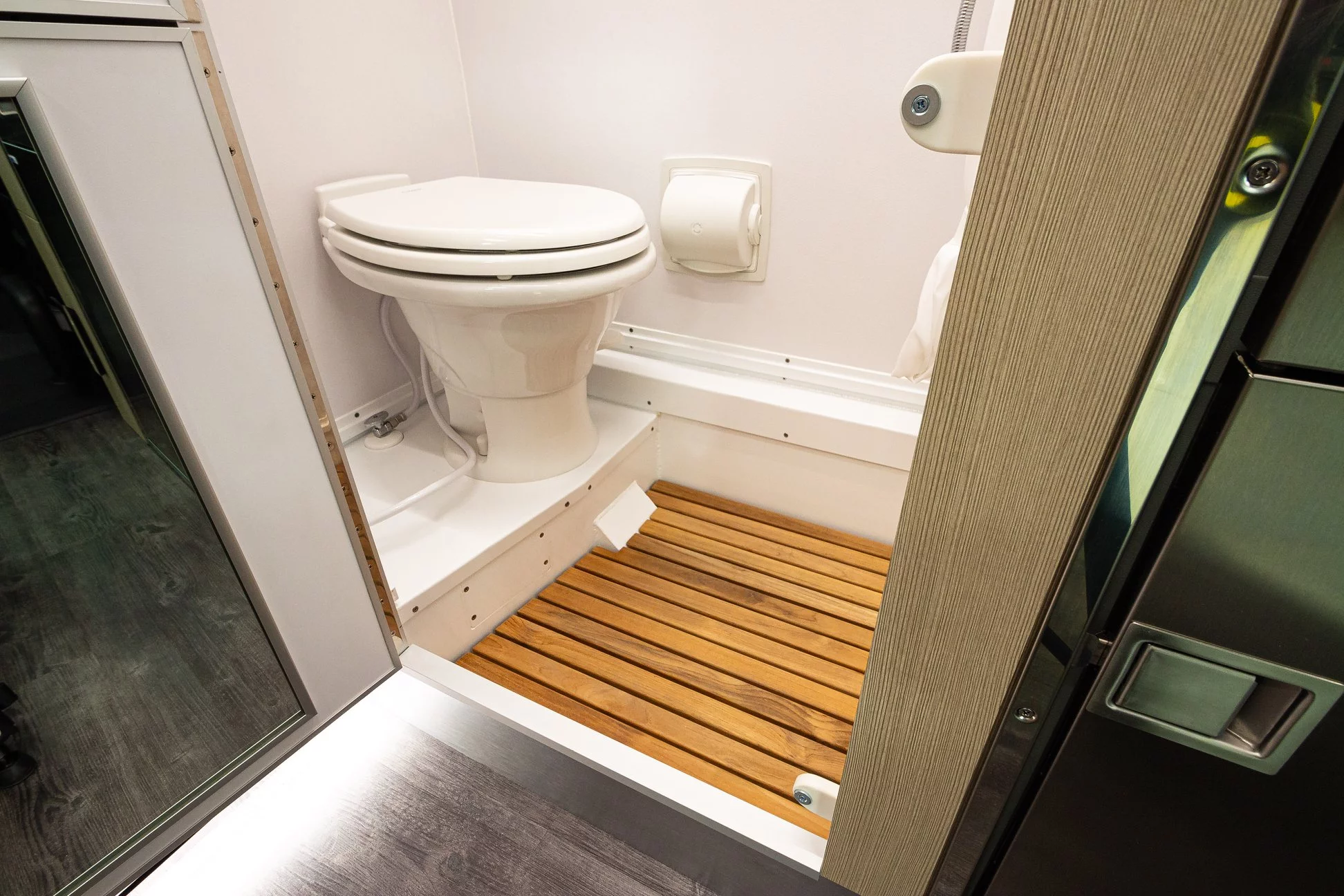 The wet bath has a toilet and a teak grate shower