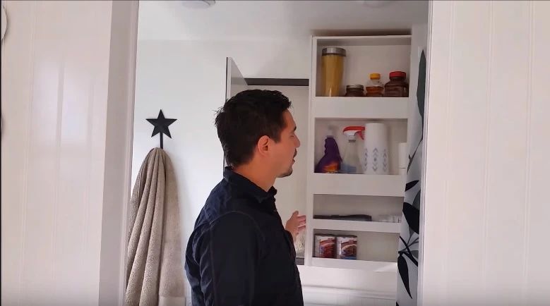 A secret storage space is hidden within the wall cavity behind the shower