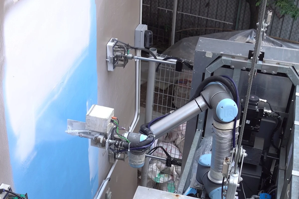 OutoBot applies white paint to an industrial building