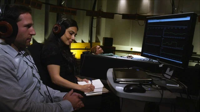 Researcher Valorie Salimpoor and colleague Mitchel Benovoy observe a volunteer as she listens to some of her favorite music