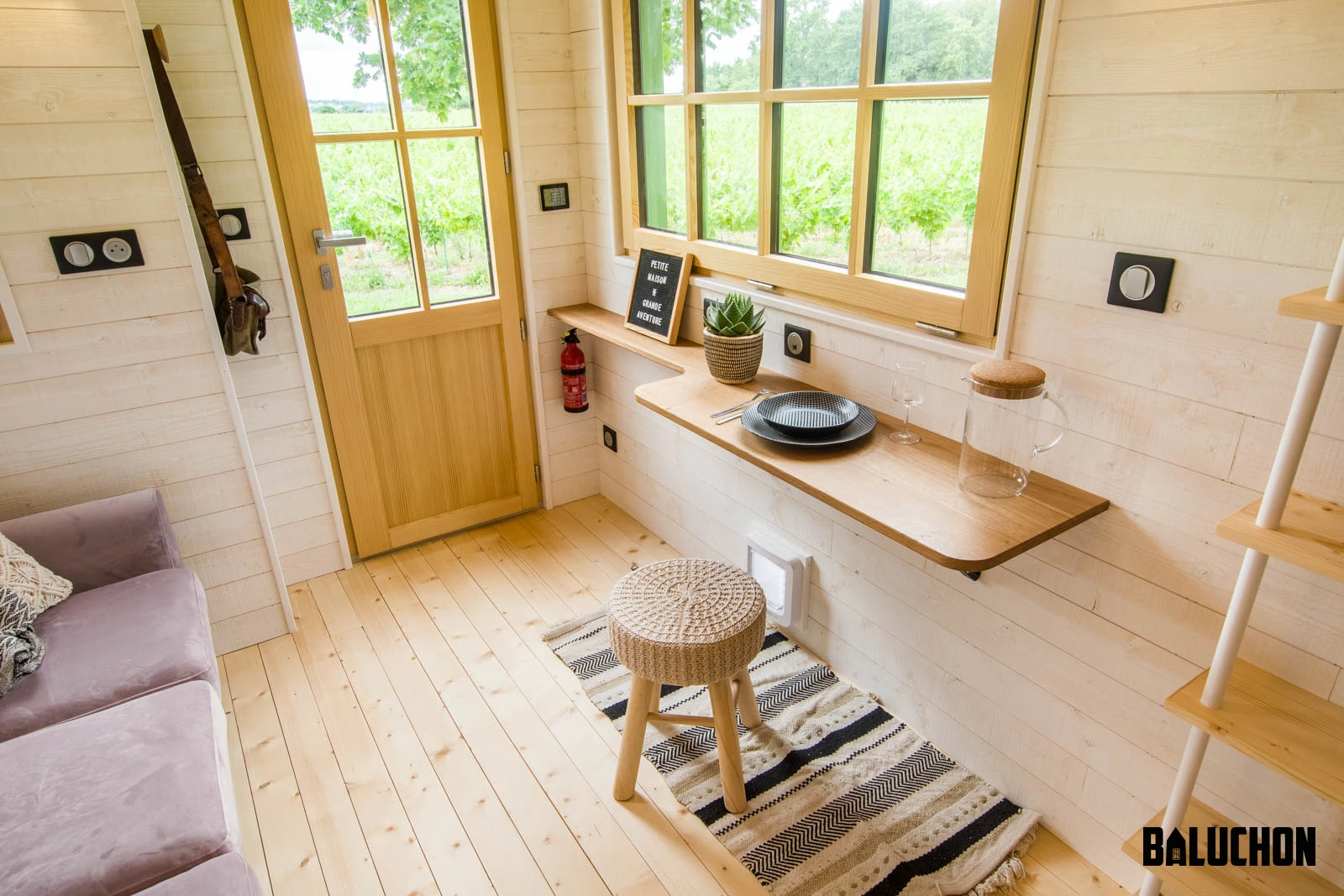 La Mésange Verte's living room includes a small desk/dining table. A cat flap is installed in the wall underneath