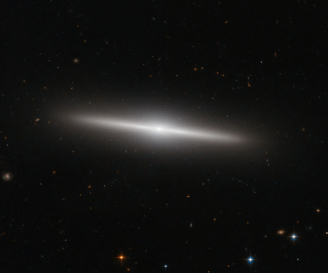 This NASA/ESA Hubble Space Telescope image shows the galaxy IC 335 in front of a backdrop of distant galaxies. IC 335 is part of a galaxy group containing three other galaxies, and located in the Fornax Galaxy Cluster 60 million light-years away