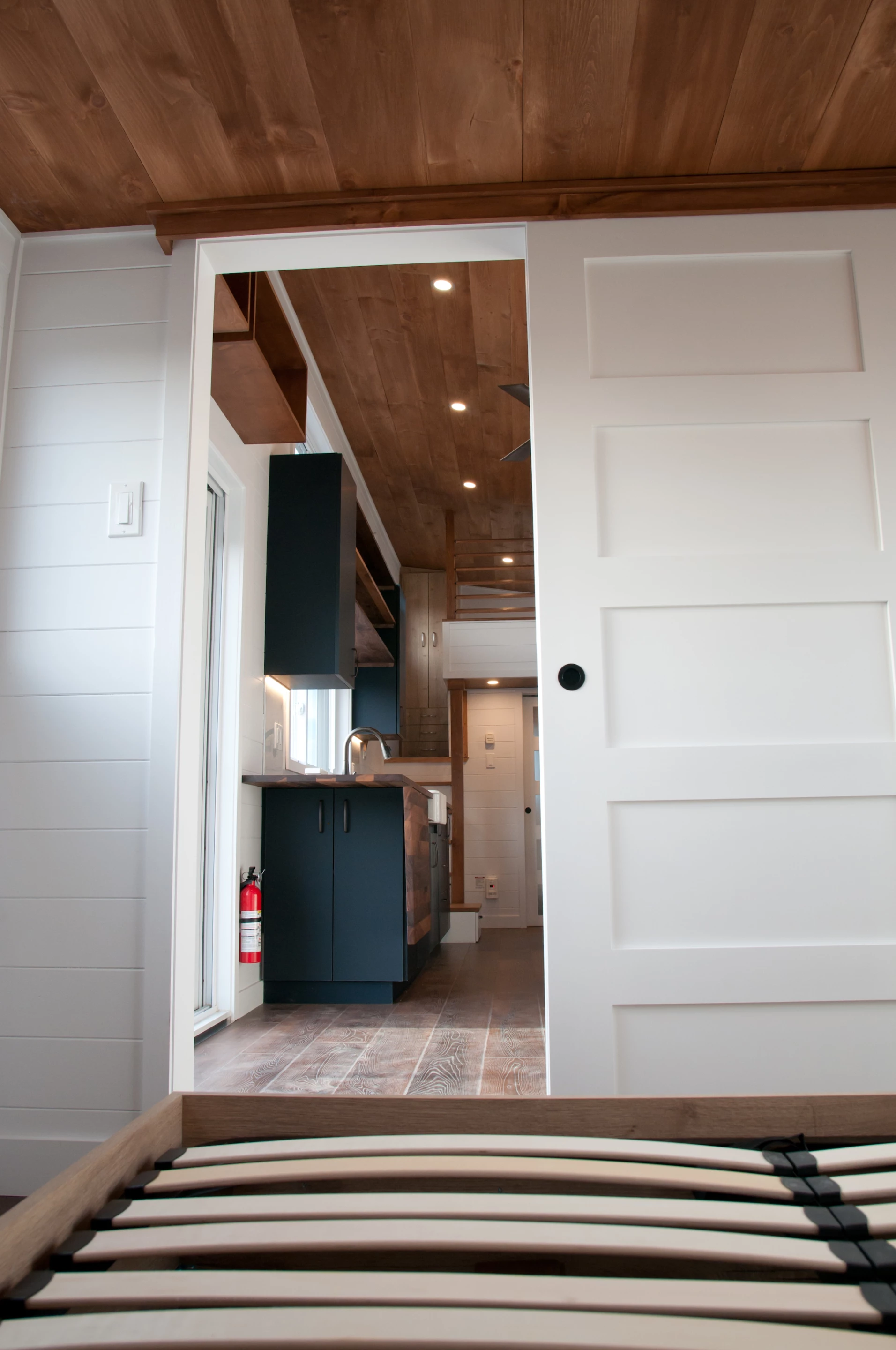 The Charme V2's downstairs bedroom is located next to the tiny house's living room and is reached by sliding door