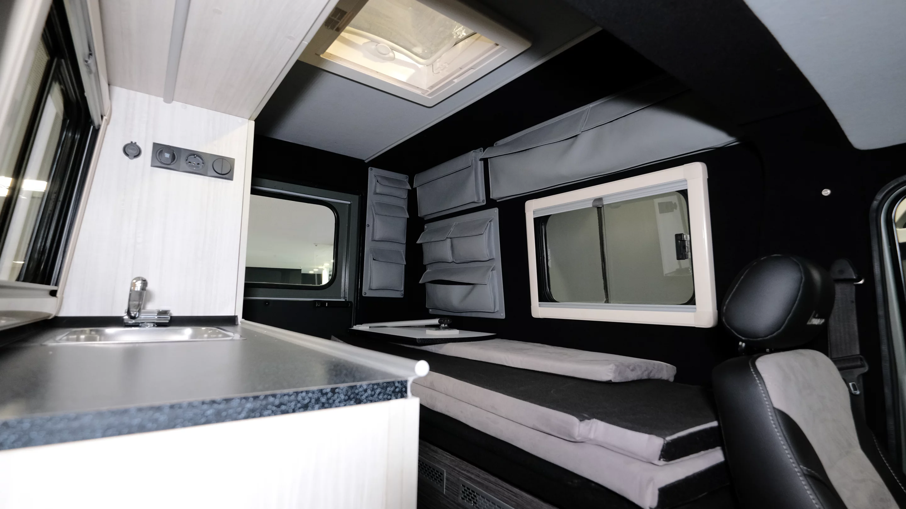 The camper conversion includes a convertible sofa-bed, kitchen counter with sink and storage