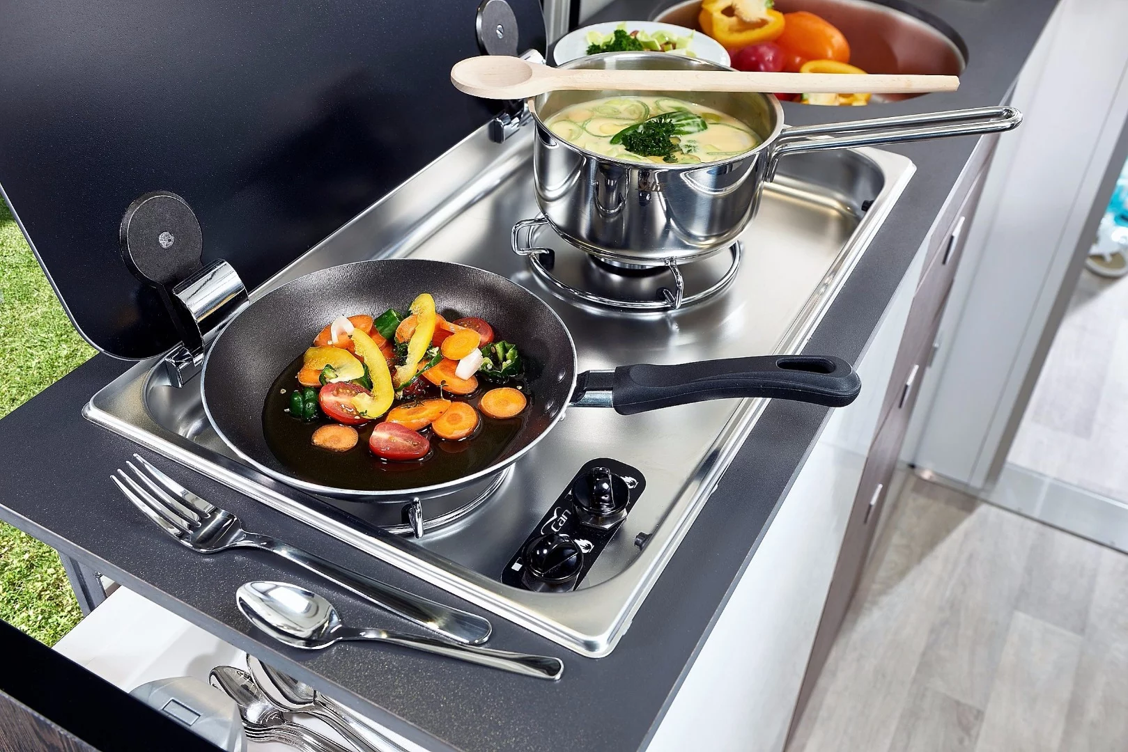 A dual-burner stove and sink with easily accessible utensils, dishes and food makes for functional cooking