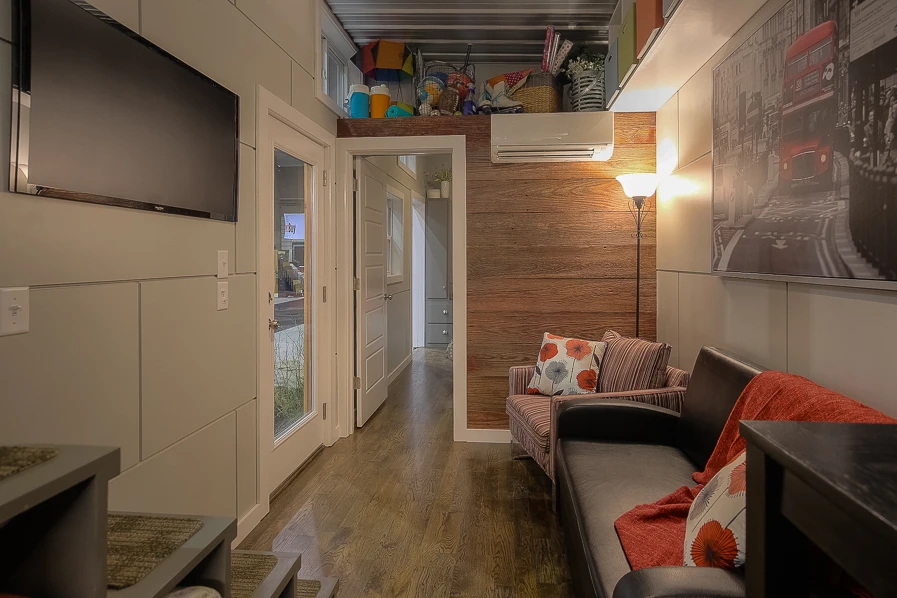 Inside, the container-based home includes a living/dining area, a relatively large kitchen and bathroom, and a bedroom on the first floor