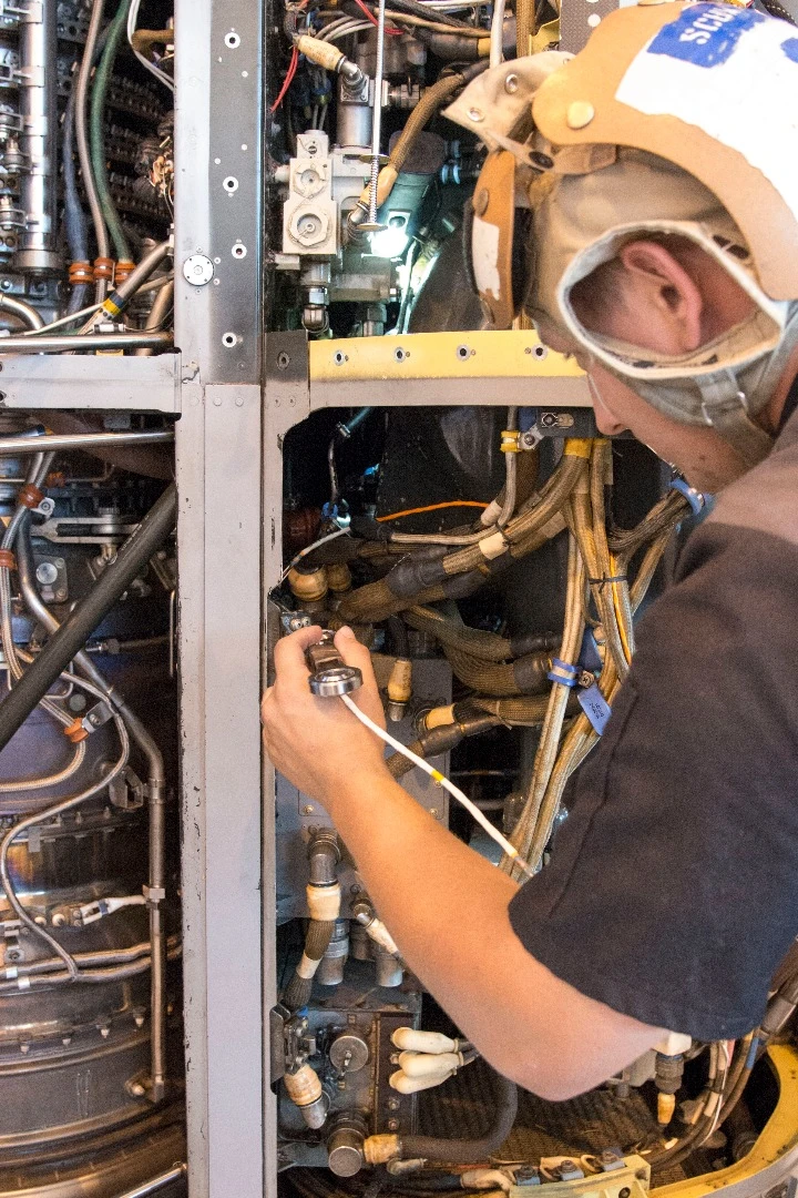 Aviation Mechanic Cody Schwarz works to install a 3-D printed titanium link and fitting on an MV-22B Osprey engine nacelle