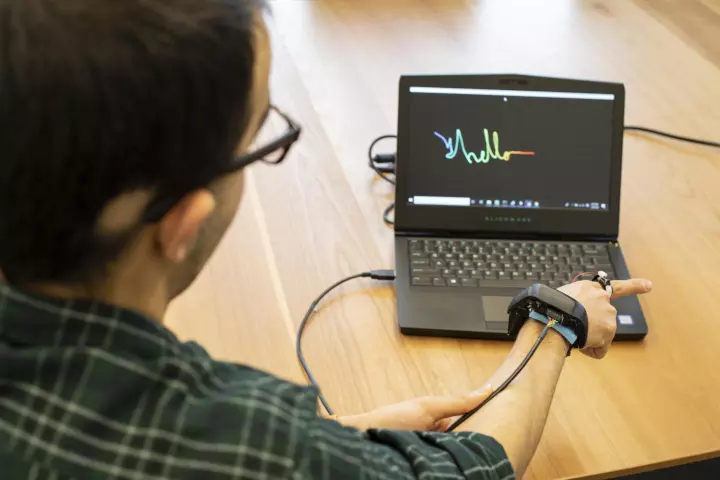 The AuraRing prototype, seen here being used to hand-write a simple message