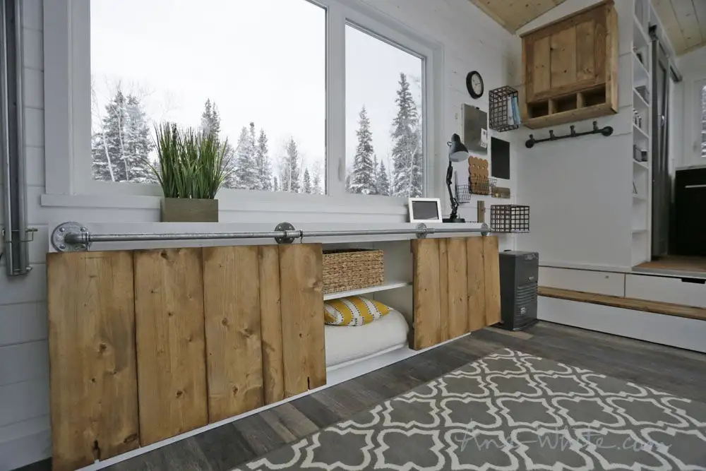 The Open Concept Rustic Modern Tiny House's storage unit can be used as two separate desks, one large desk, or a dining table