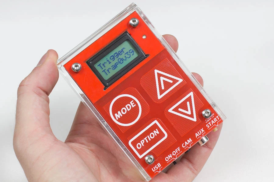 The upper face has four touch-sensitive buttons below a simple grayscale LCD display, with an LED indicator to its right