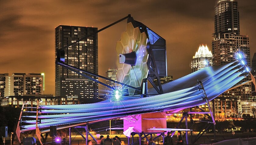 The full scale model of JWST in front of the Austin skyline