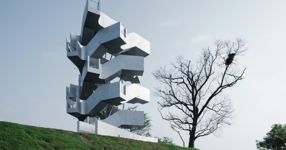 A tall, twisting steel tower with two interlocking spiral staircases and multiple viewing platforms, situated on a low hill overlooking a flat wetland landscape.