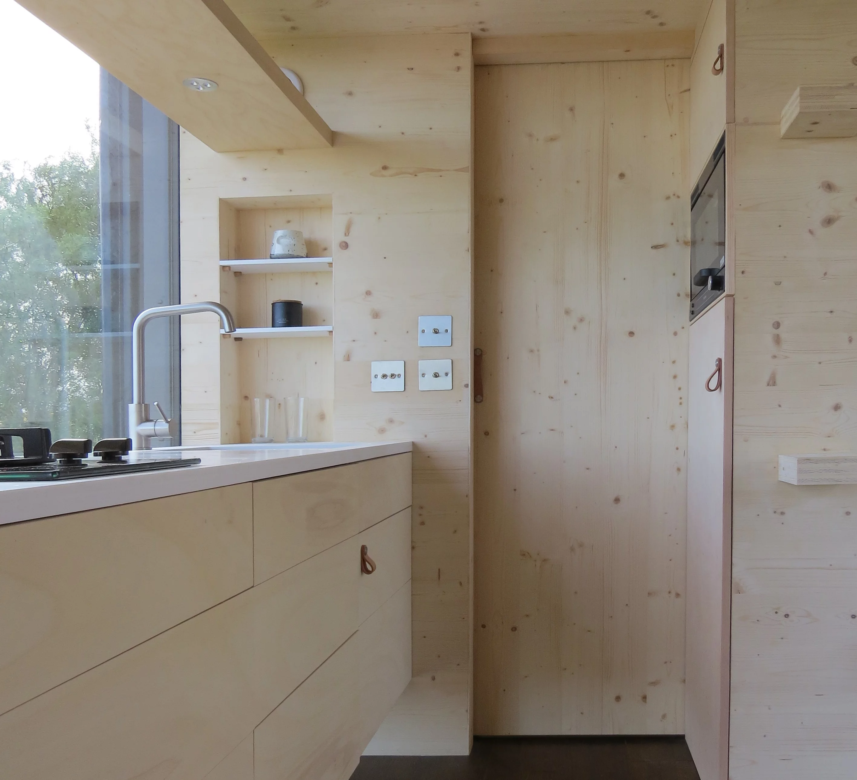 The Long Shed's kitchen includes a two-burner propane-powered stove, oven, fridge, sink, and cabinetry