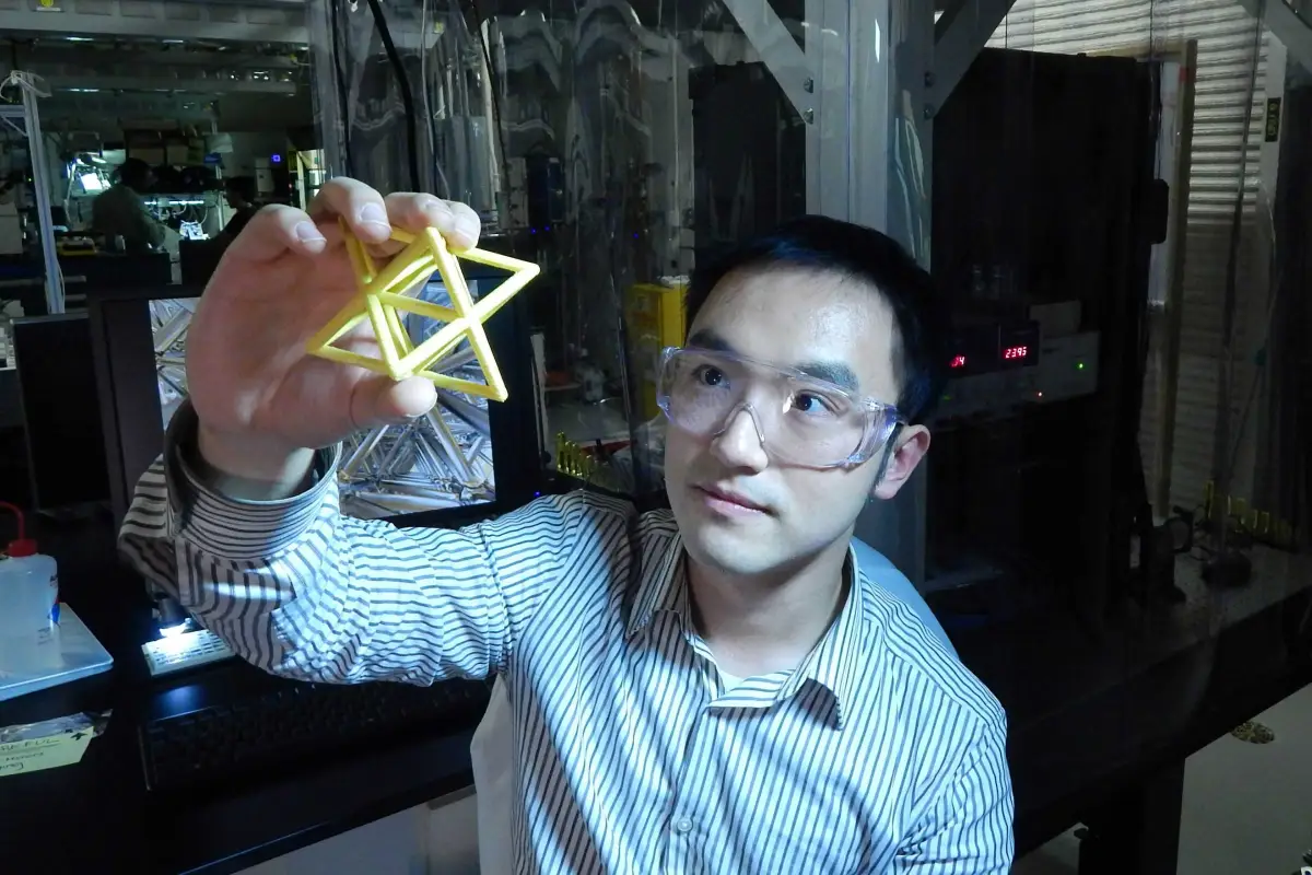 Lawrence Livermore Engineer Xiaoyu "Rayne" Zheng studies a macroscale version of the unit cell that makes up the the ultralight, ultrastiff material (Image: Julie Russell/LLNL)