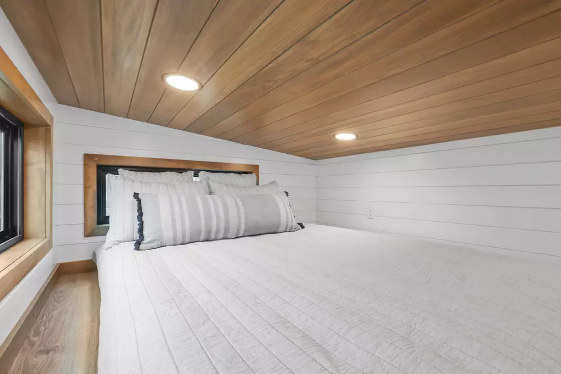 The Coastal Modern's bedroom is a typical tiny house-style loft space with a low ceiling