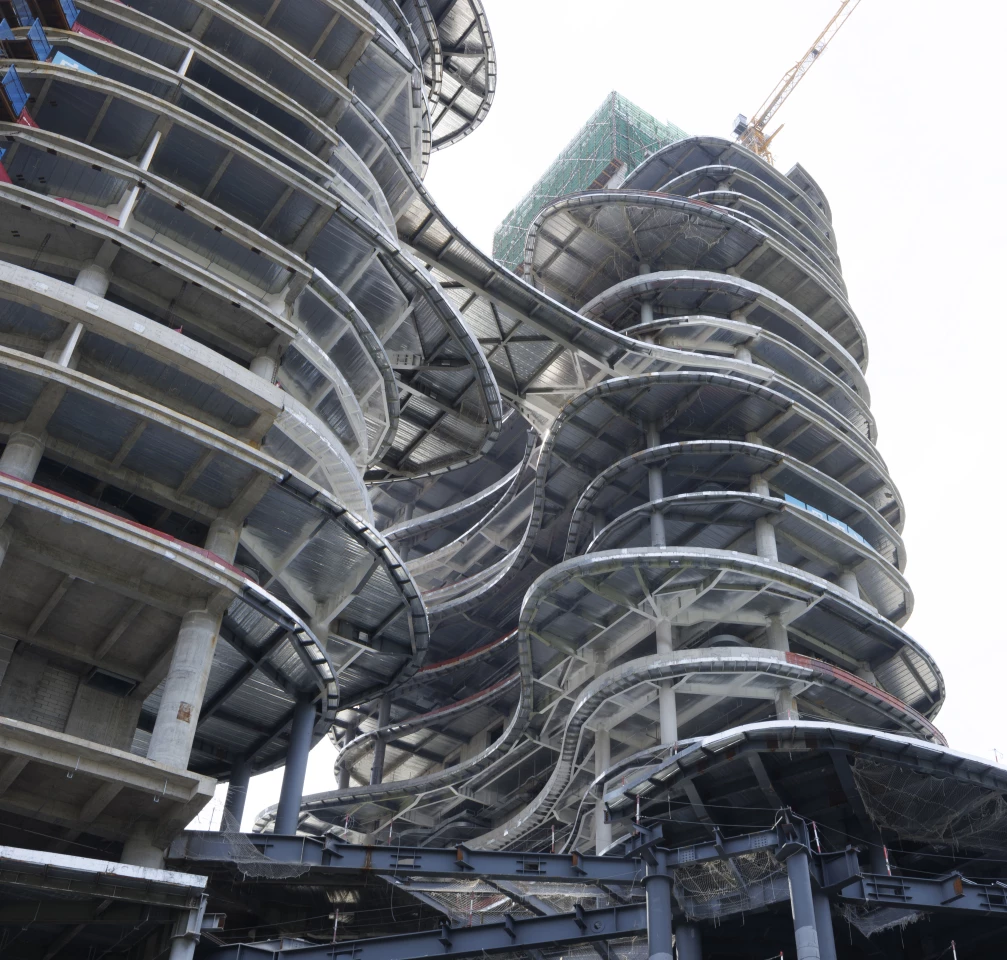 CDATA[## A Building That Looks Like It's From Another World
You might mistake this extraordinary structure for an alien megastructure straight out of a sci-fi movie, but the **Yidan Center** is very real and nearing completion in Shenzhen. Designed by the renowned **Zaha Hadid Architects**, it's set to become a hub for the Chen Yidan Foundation, featuring offices, exhibition spaces, and collaboration areas.
## Inspired by Nature's Grandeur
The design draws inspiration from the surrounding mountains and canyons of Shenzhen, which have historically served as natural pathways. At its heart is a massive void, reminiscent of a canyon, that not only defines its striking form but also serves a practical purpose: allowing **daylight to penetrate deep into the interior**. This void is part of a structure composed of two tower-like volumes that converge at the top, echoing the studio's previous projects like Morpheus and Opus.
![The Yidan Center is currently nearing completion and its basic structure is finished