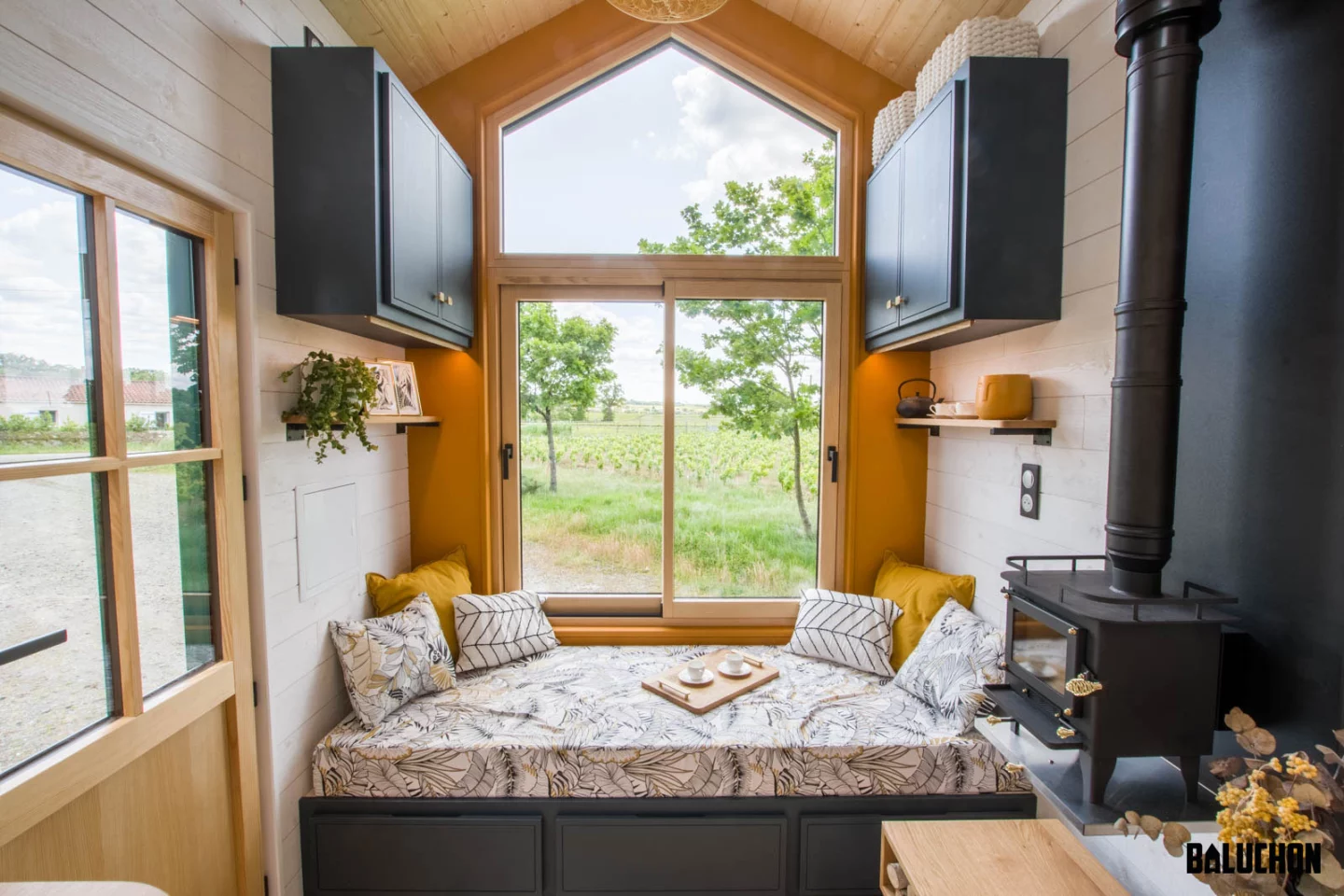 The Mina tiny house's living room includes a large window seat that doubles as a guest bed, in a pinch