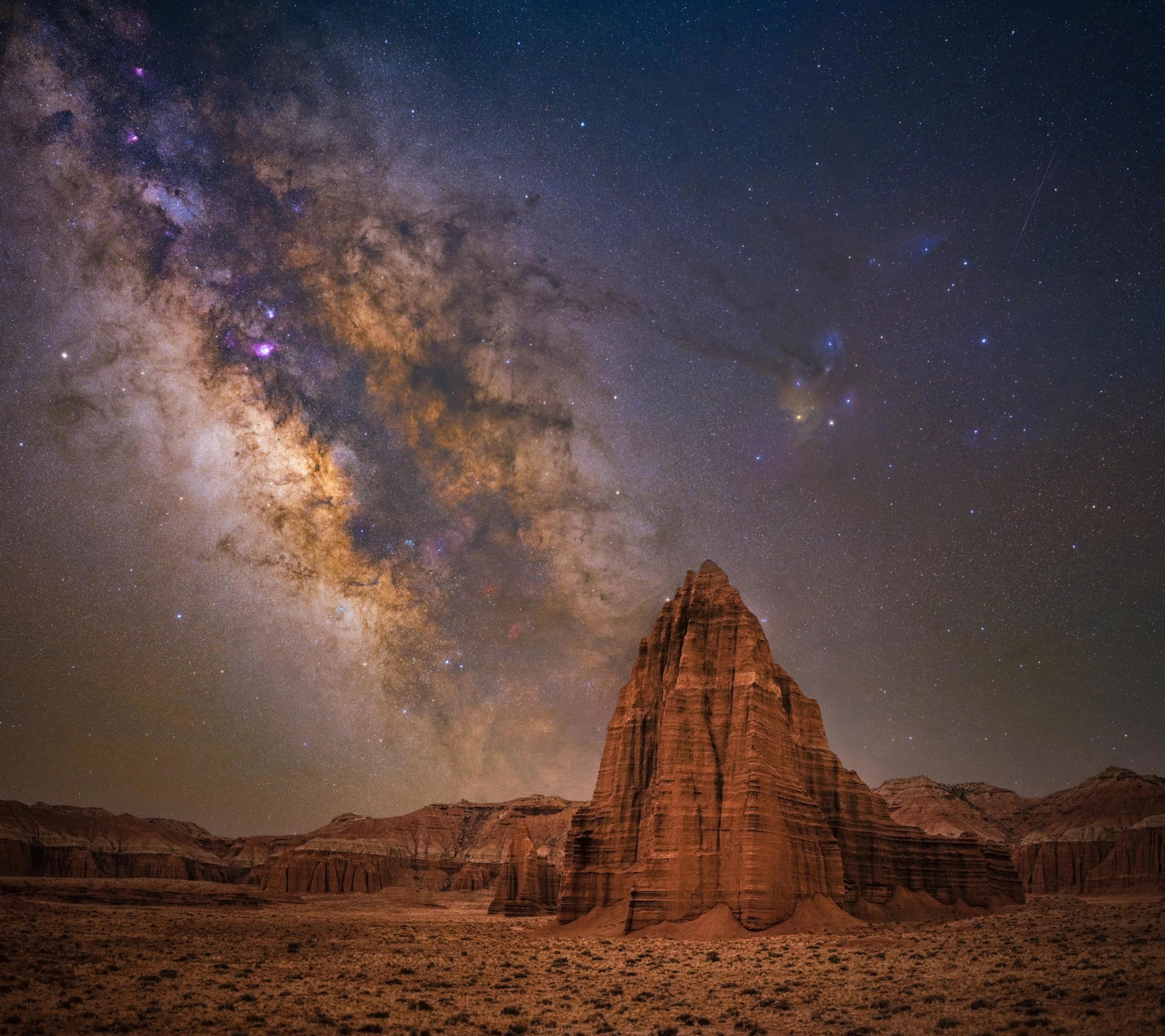 Temple of the Sun, shot in Utah, USA. A prehistoric sandstone structure rises from the desert floor of the Capitol Reed National Park, beneath the cloudy Milky Way