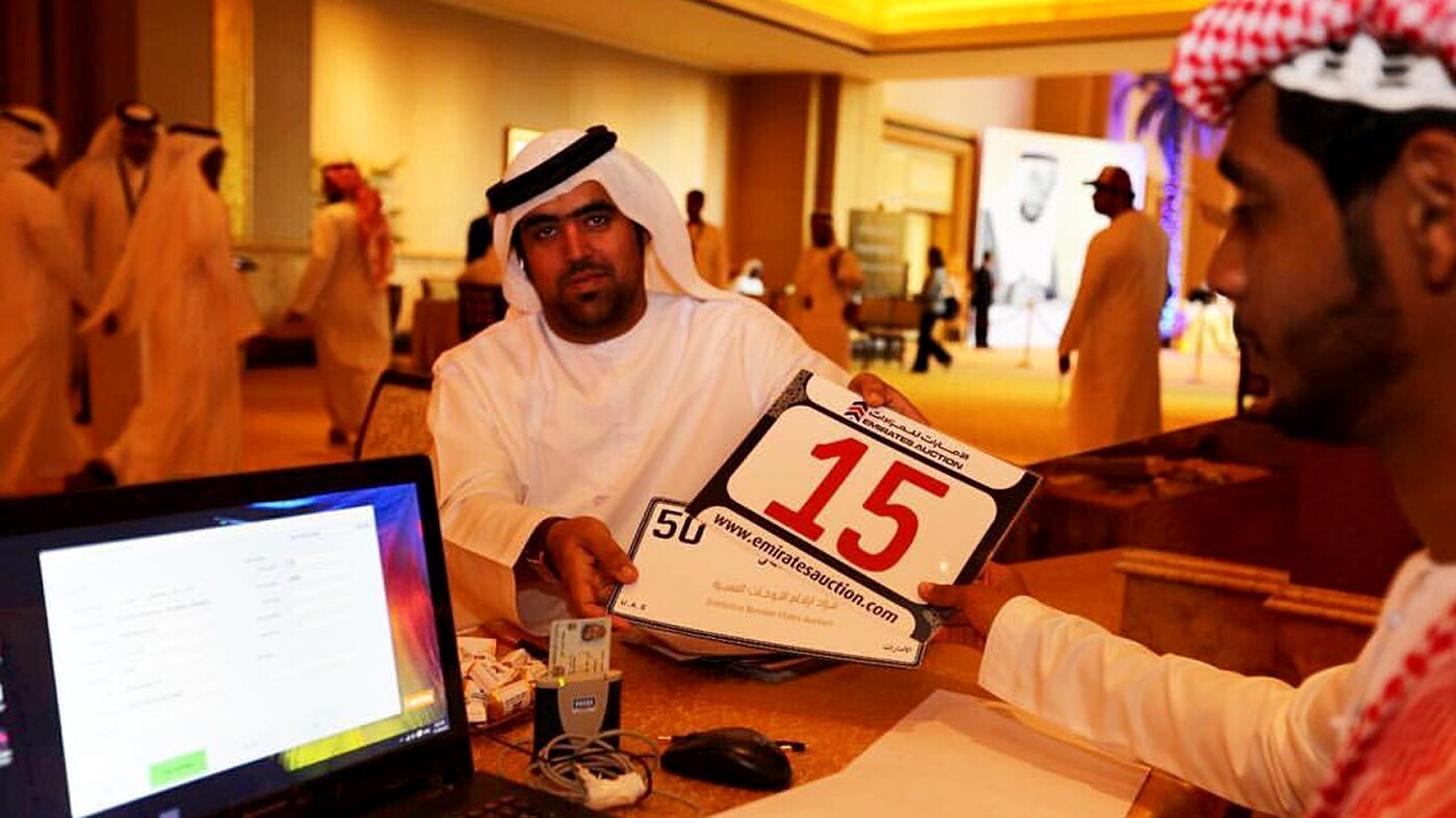 A young Emirati picks up the plate he has just purchased at auction