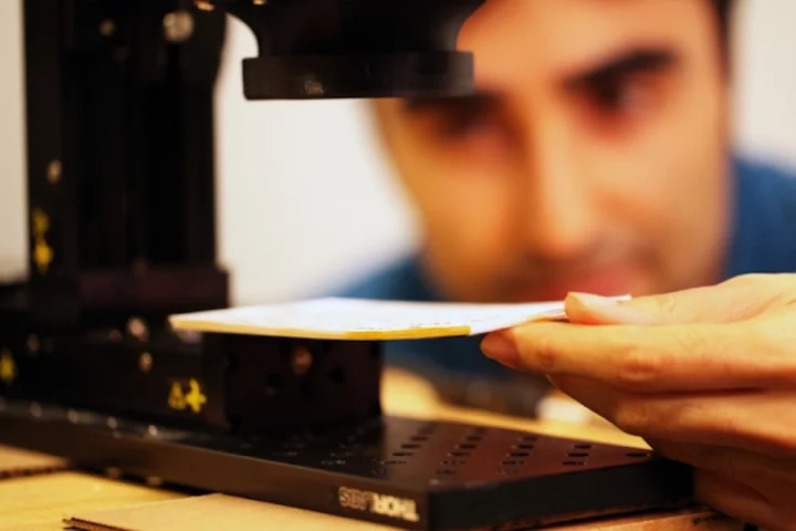 The MIT researchers hold a stack of paper underneath the prototype imaging device