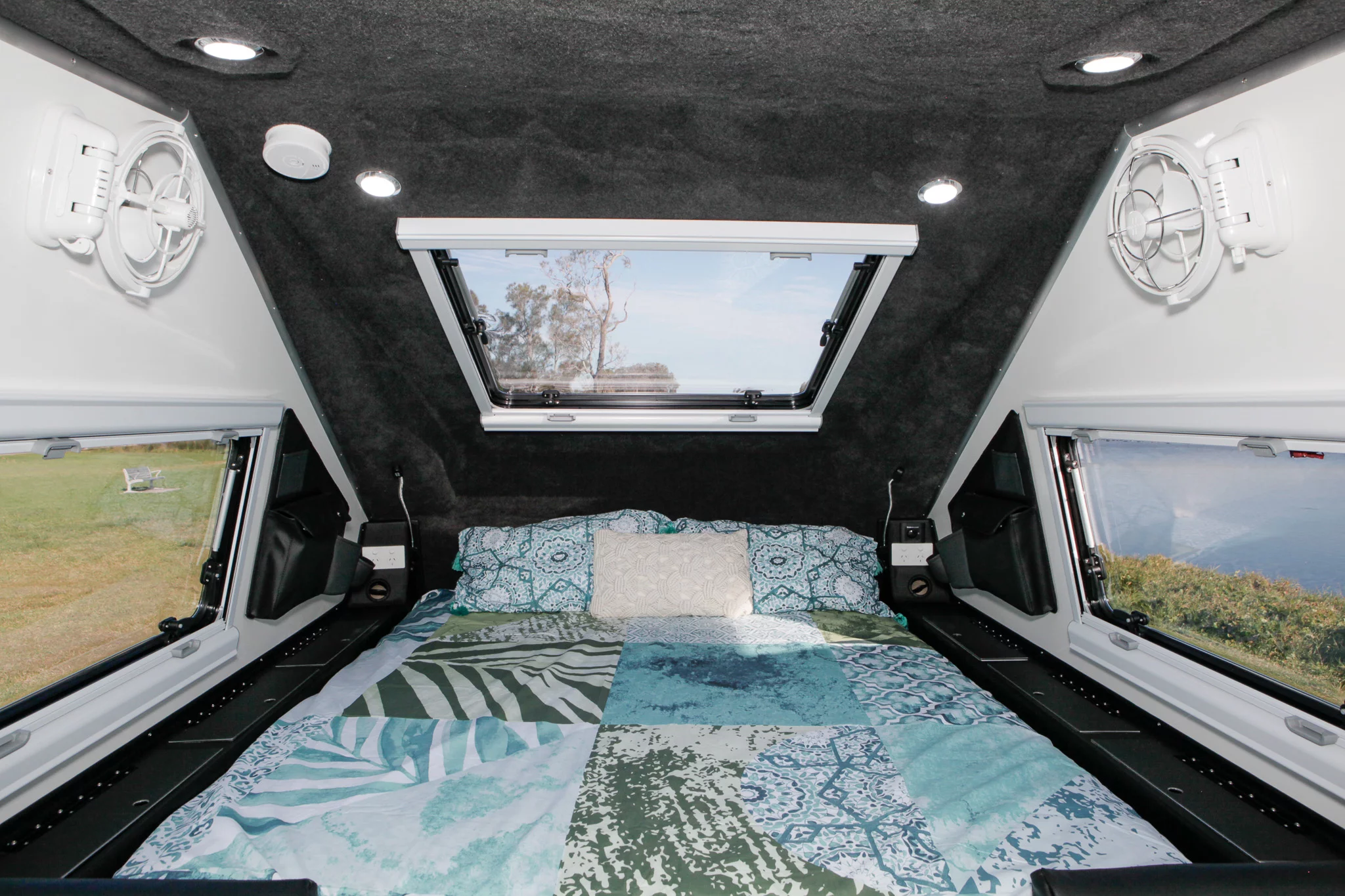 The queen bed is set below a large skylight and between storage compartments that can be ordered with or without keyed locks