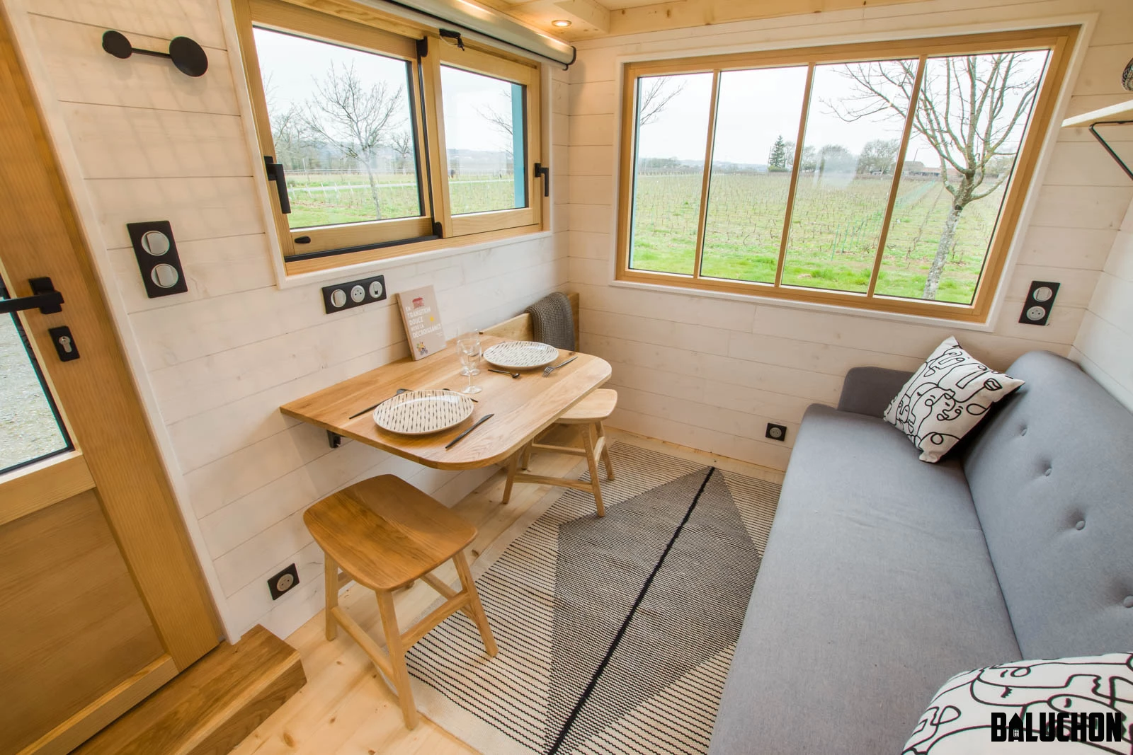 The Tiny house Kalzennig's living room includes a folding dining table and a pull-down screen for a movie projector