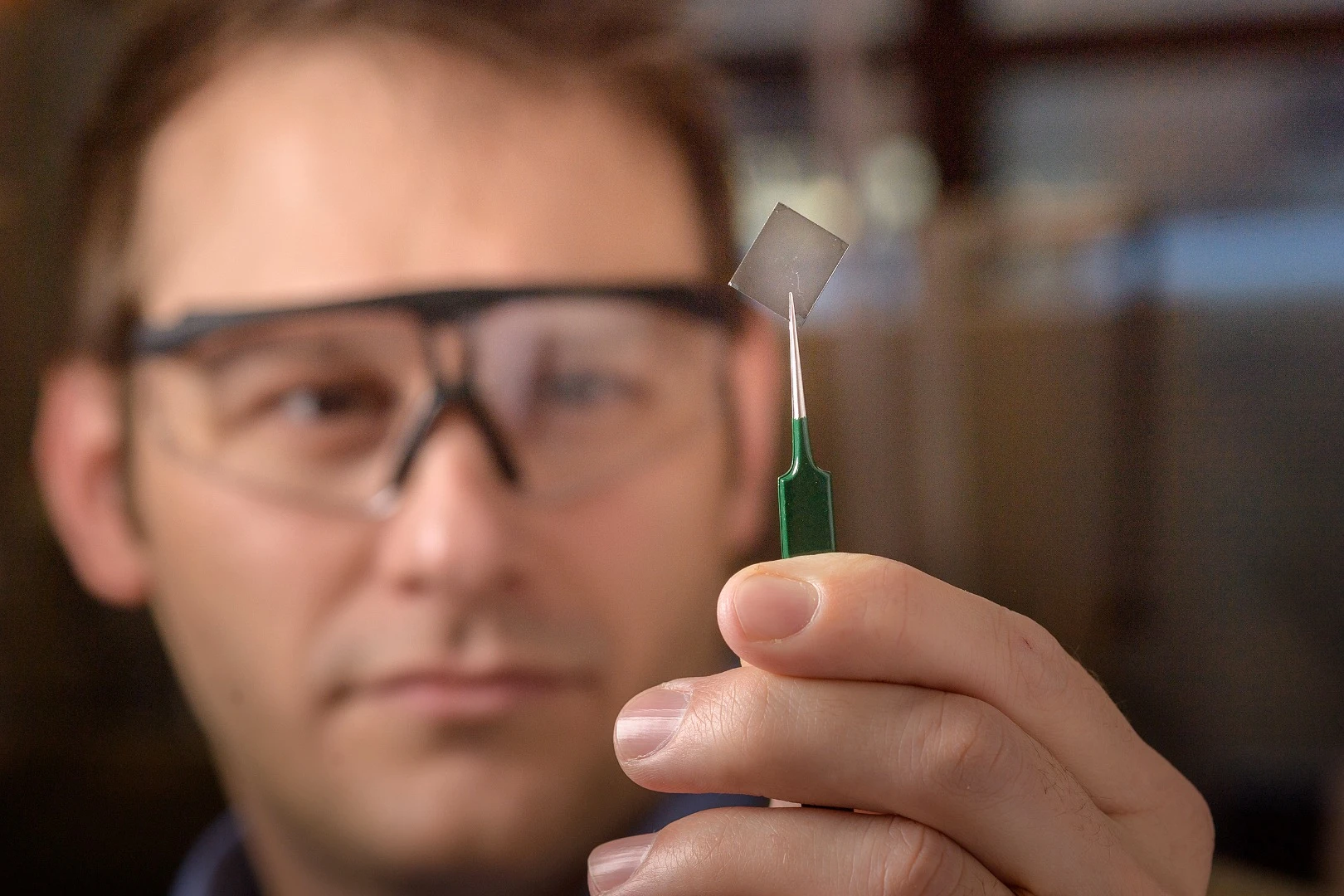 Purdue researcher Brett Savoie holds up a sample of the new transparent, conductive polymer