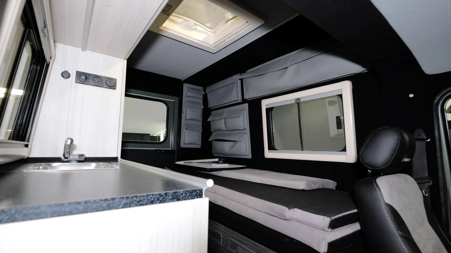 The camper conversion includes a convertible sofa-bed, kitchen counter with sink and storage