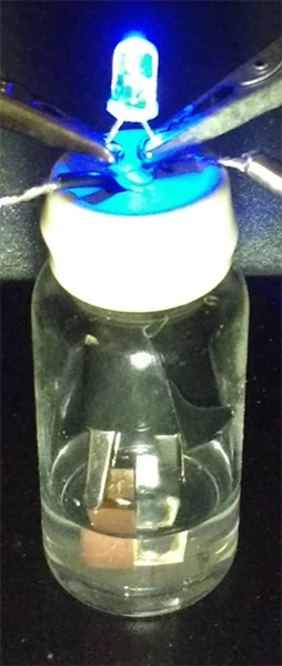 A prototype of the scrap-metal battery powering a small light