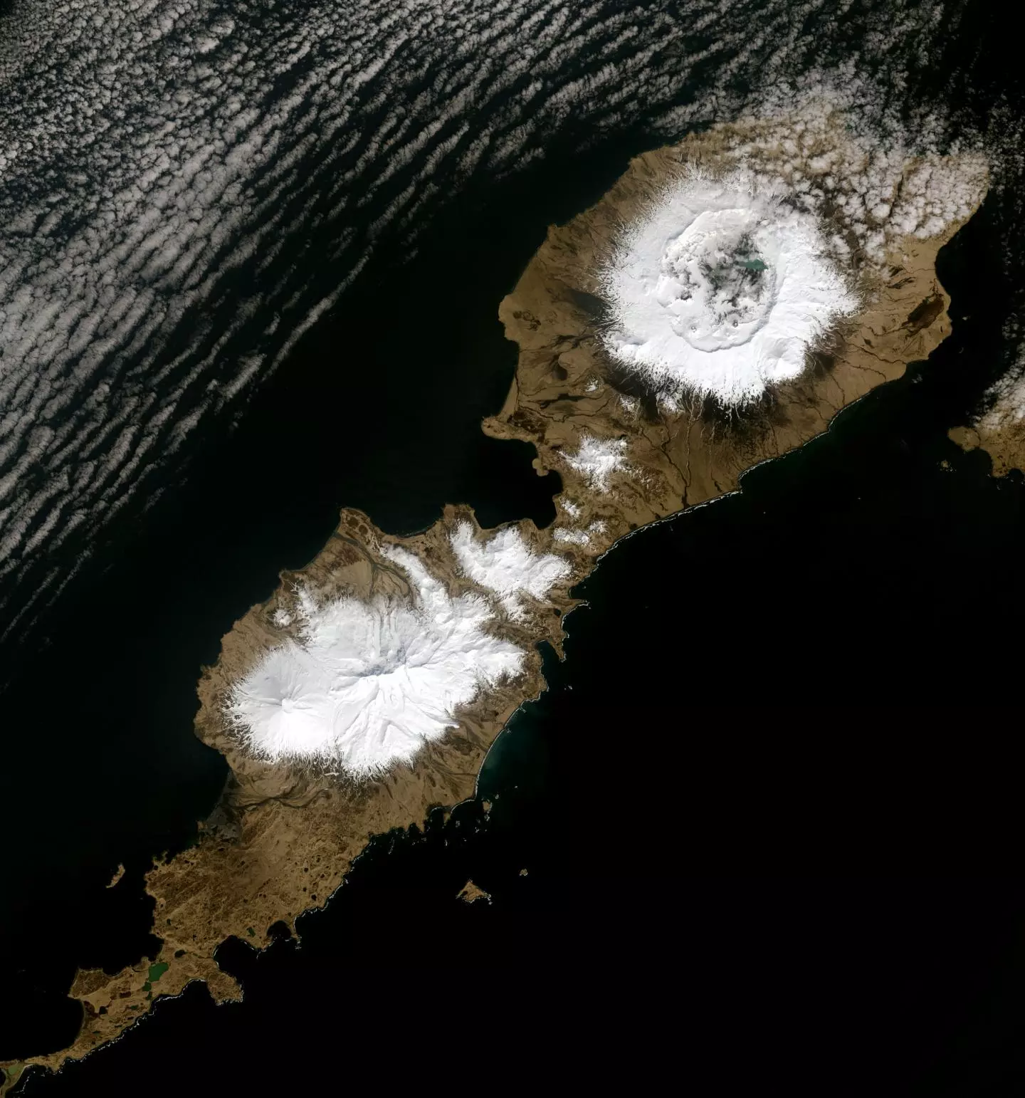 The 10-km wide caldera which formed as a result of the Okmok eruption in 43 BCE can be seen in the upper snowy region of this image