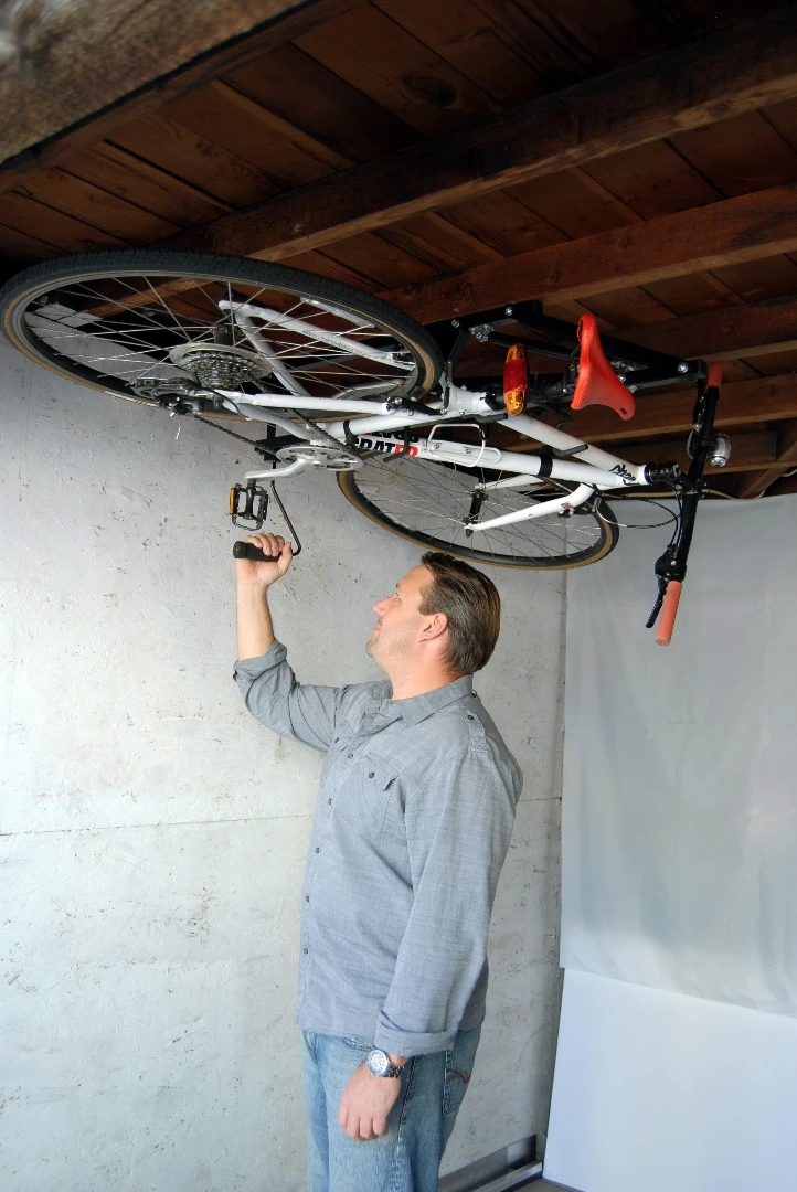 Once it is secured, you push upwards with a handle to have the Hide-A-Ride fold in on itself and the bike locked into place against the ceiling
