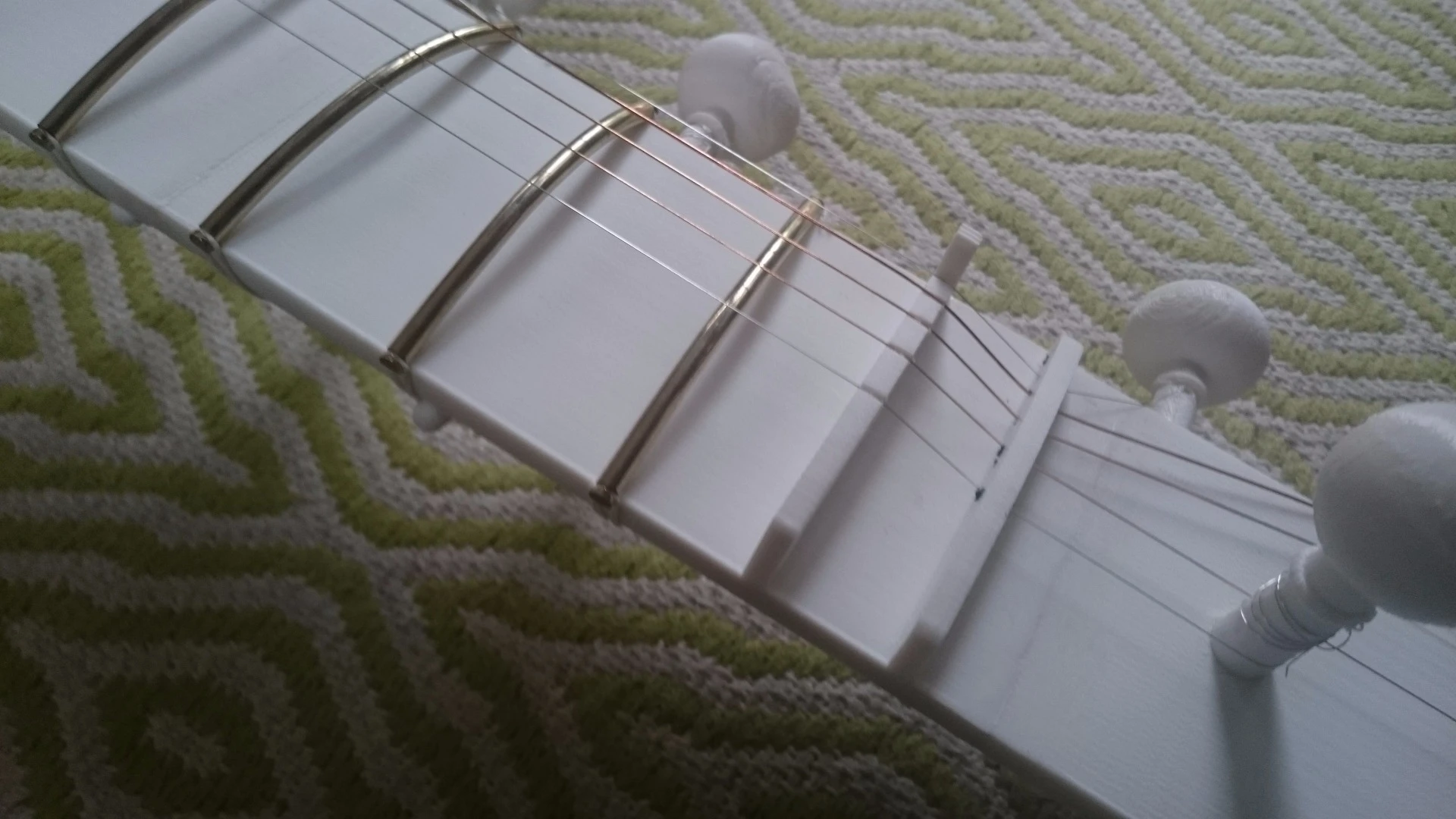 Strings fed over non-printed frets to the tuning pins at the head