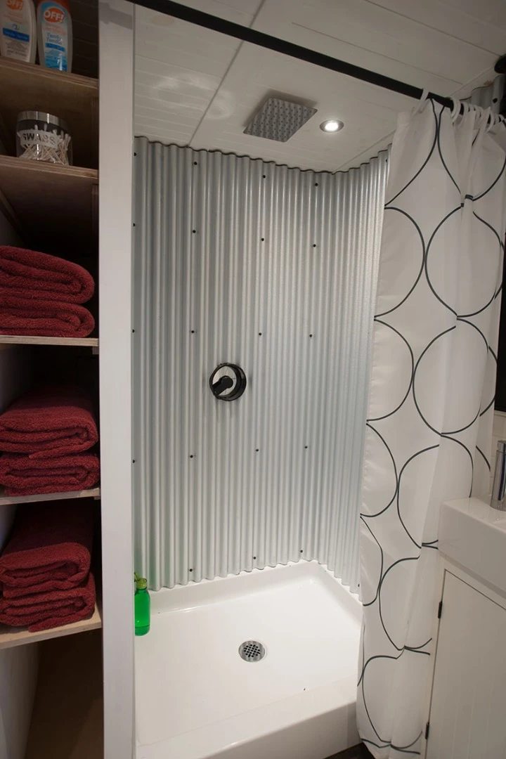 The bathroom of the Greenmoxie Tiny House includes a shower, sink, and composting toilet