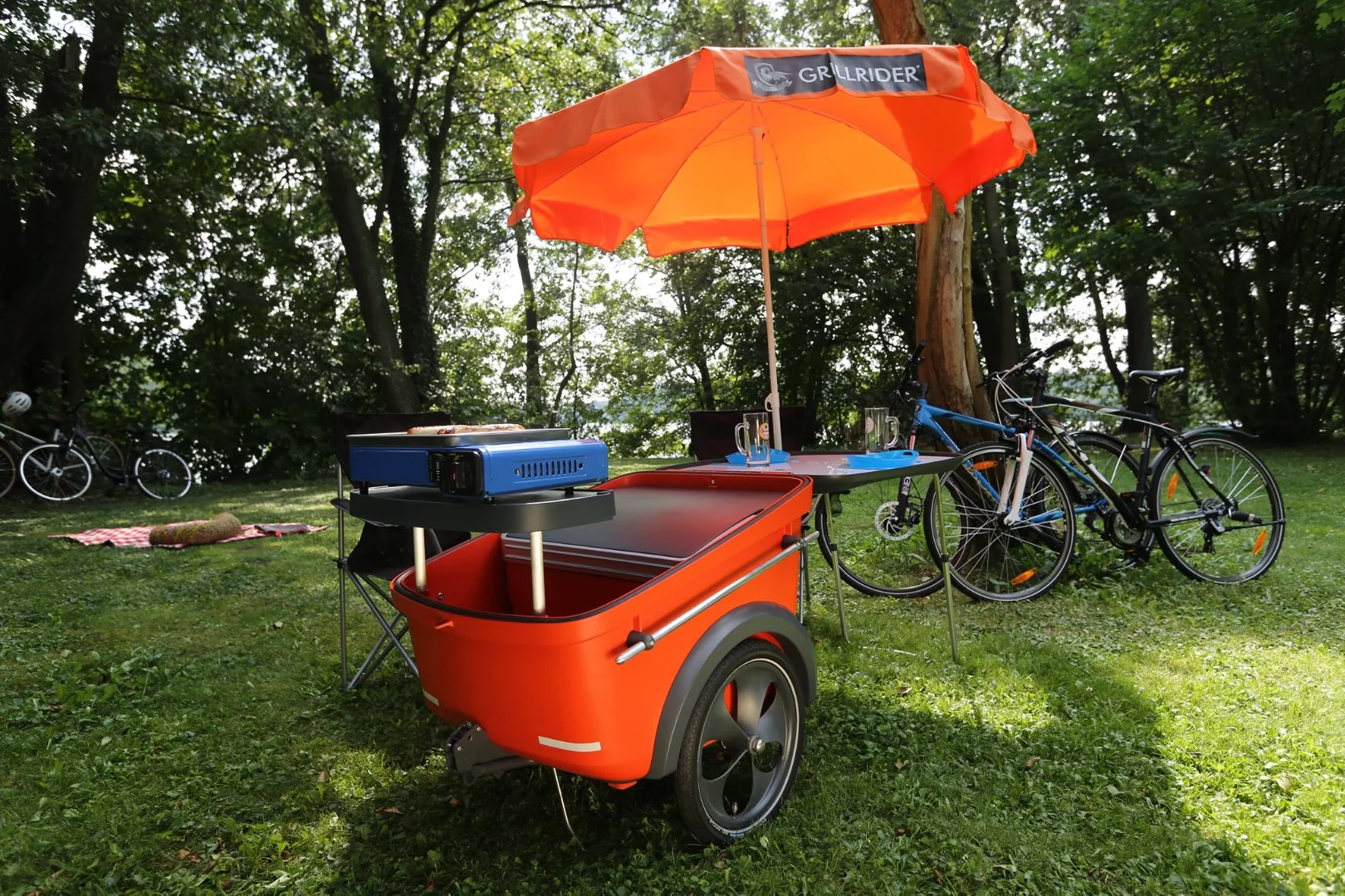 No mention of an umbrella, but the shelved grill, fold-out table and cooler are highlights of the Grillrider design