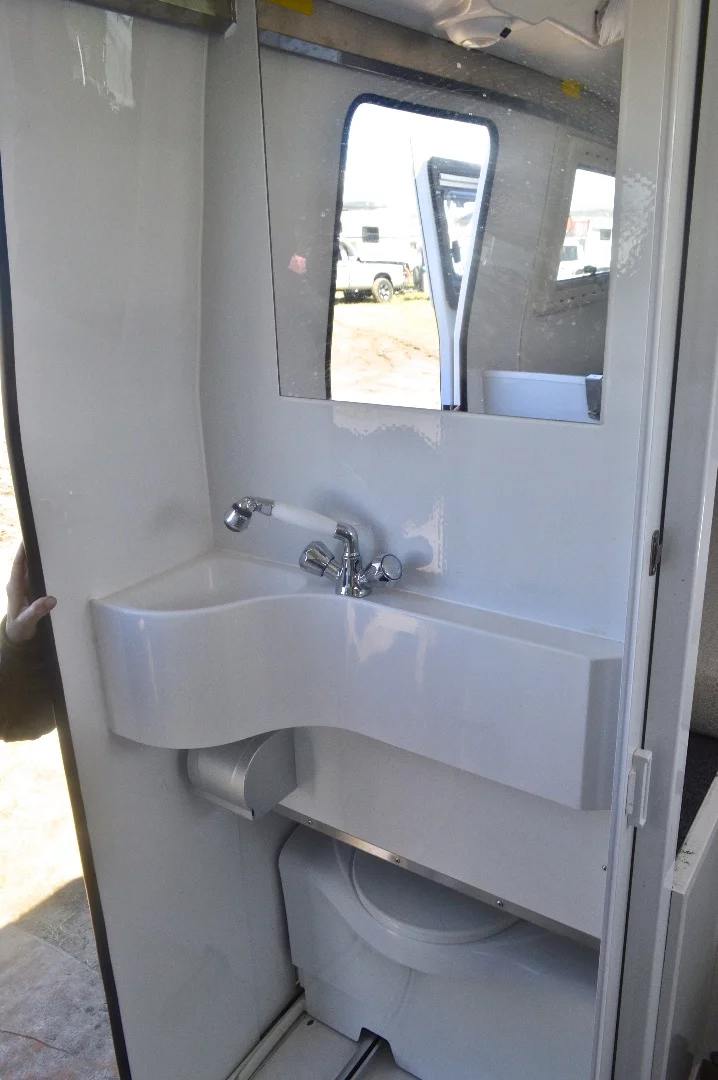 The bathroom has a shower, sink and slide-out toilet