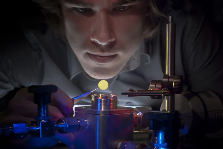 Eric Glowacki, one of the membrane's inventors, is pictured holding the membrane that changes permeability with different colors of light (Image: University of Rochester)