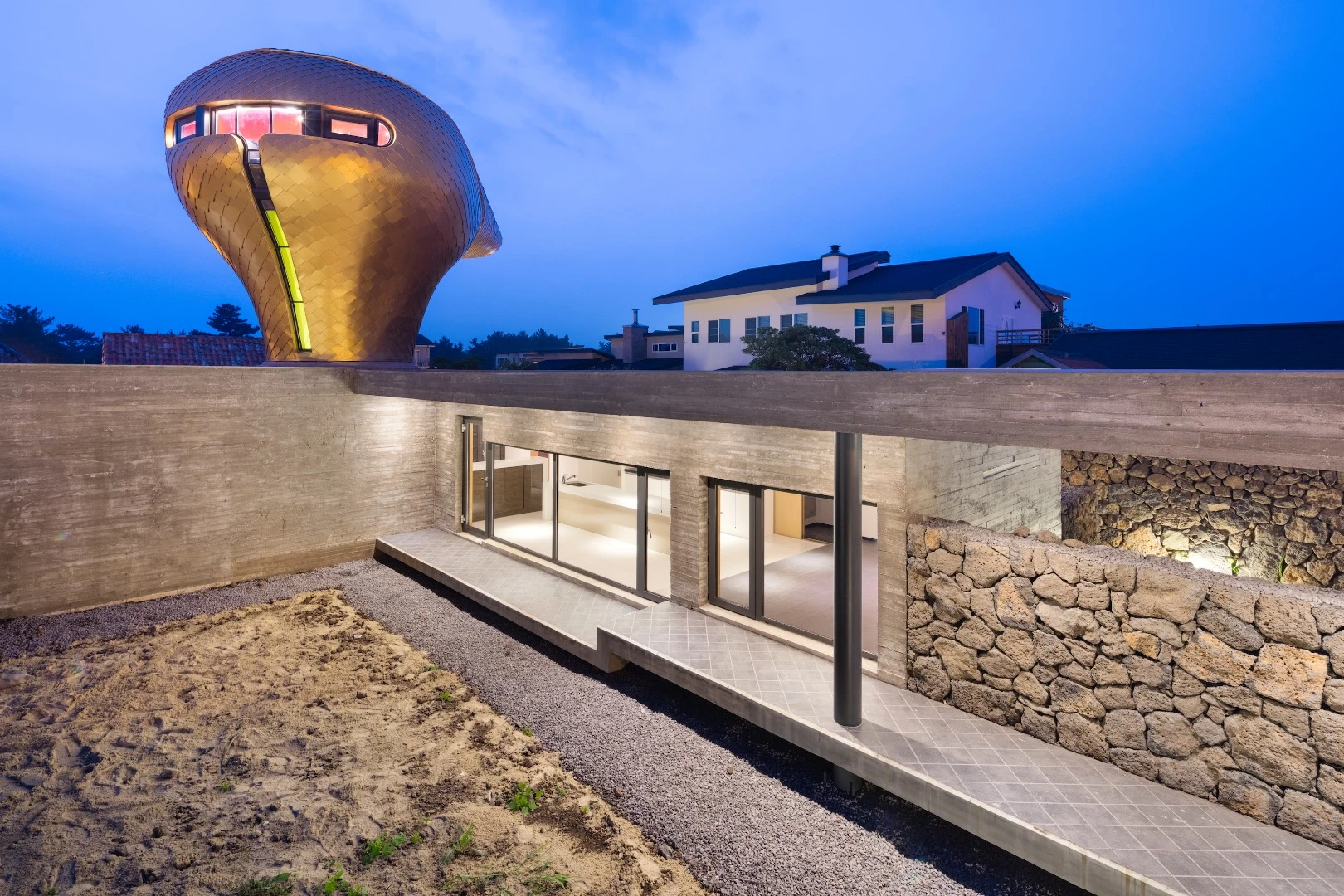 The Wind House project comprises three low-lying holiday homes dominated by a large golden structure