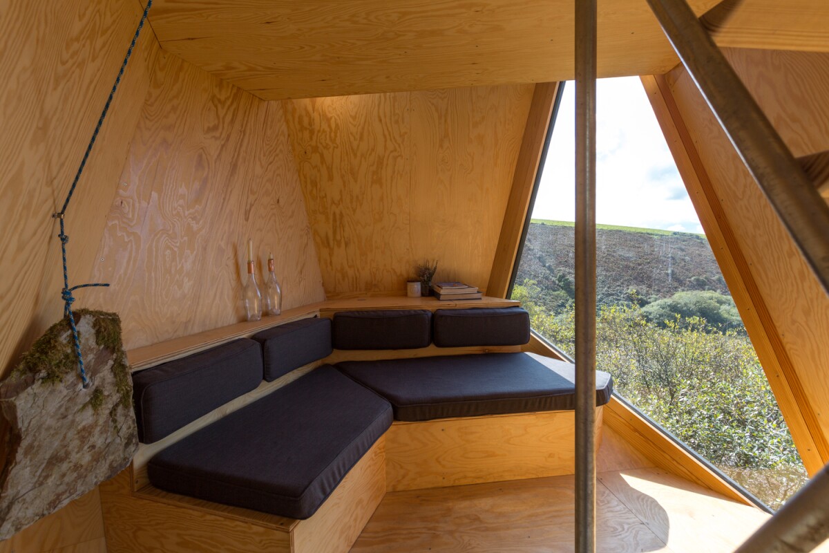Each cabin accommodates up to two guests and features a cozy lounge with log fire and large triangular window overlooking the serene landscape